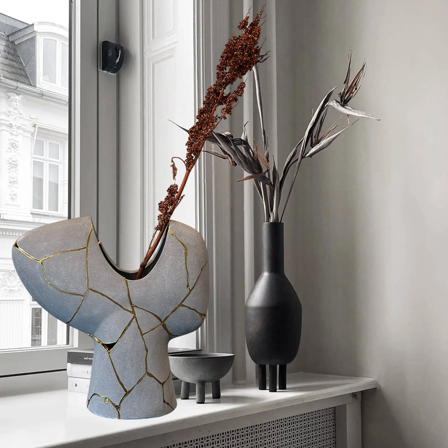Modern Kintsugi Novak Vase in gray with hand-painted gold repairs, displayed on white ledge with dried floral arrangement