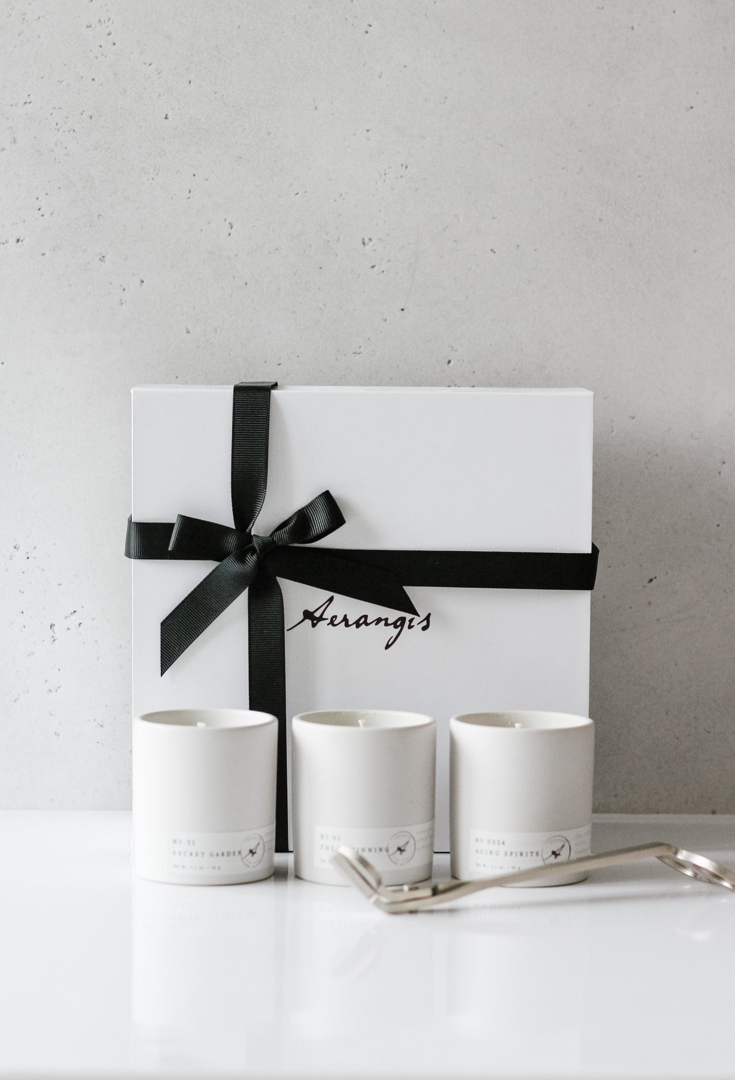 Aerangis Discovery Journey Gift Set with three mini white candles and black ribbon tied white gift box on white surface