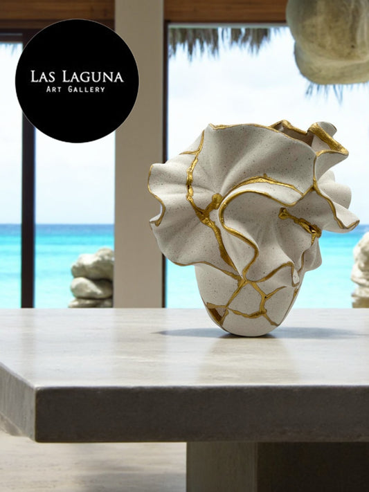 Ceramic vase with organic ruffled design and gold repair accents displayed on light stone table by ocean view window