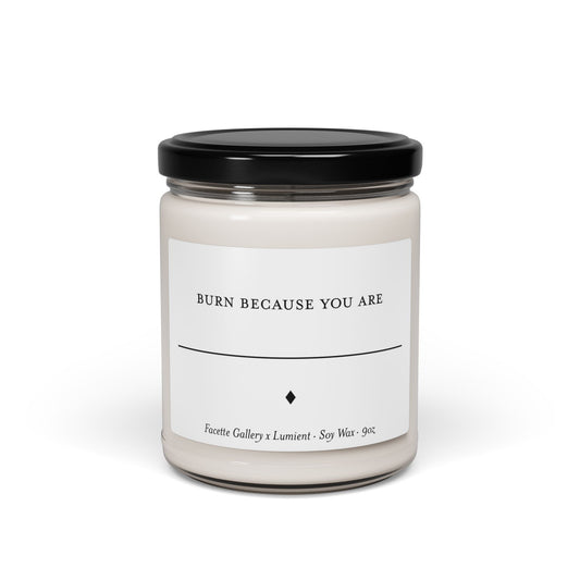 9oz white soy candle in clear glass jar with black lid, labeled "Burn Because You Are" by Facette Gallery and Lumient