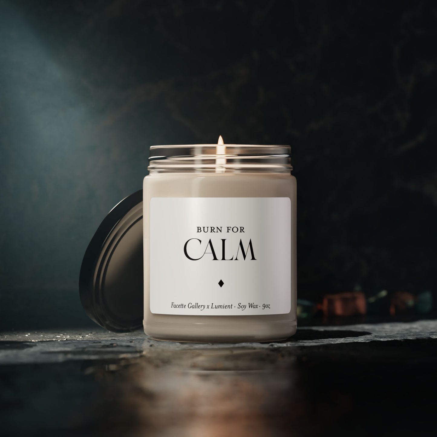 Lit 9oz soy wax candle in clear glass jar with black lid and "Burn for Calm" label on dark background