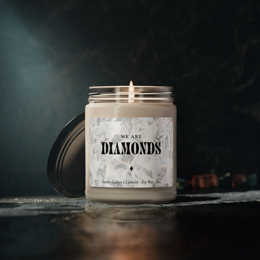 Facette Gallery Signature 'We Are Diamonds' soy candle in 9oz glass jar with lit wick and black lid on dark surface