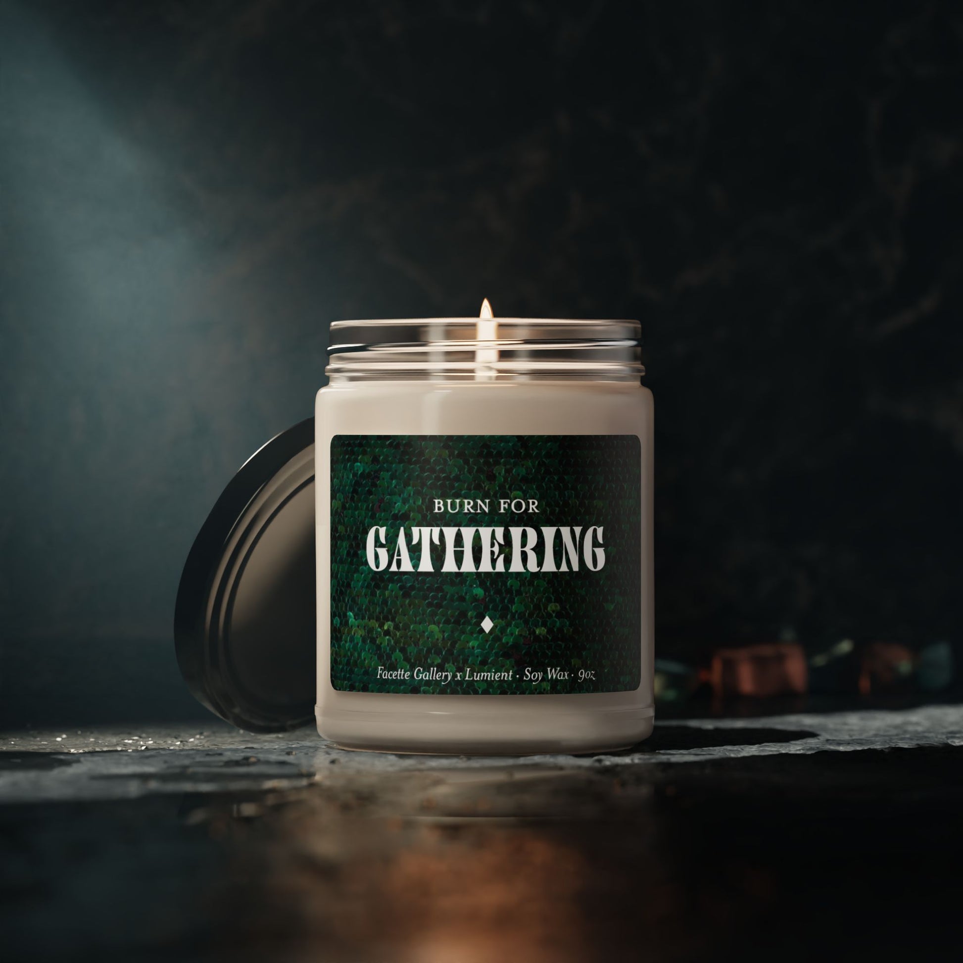 9oz soy wax candle in glass jar with green sequin label "Burn for Gathering" and black lid on stone surface