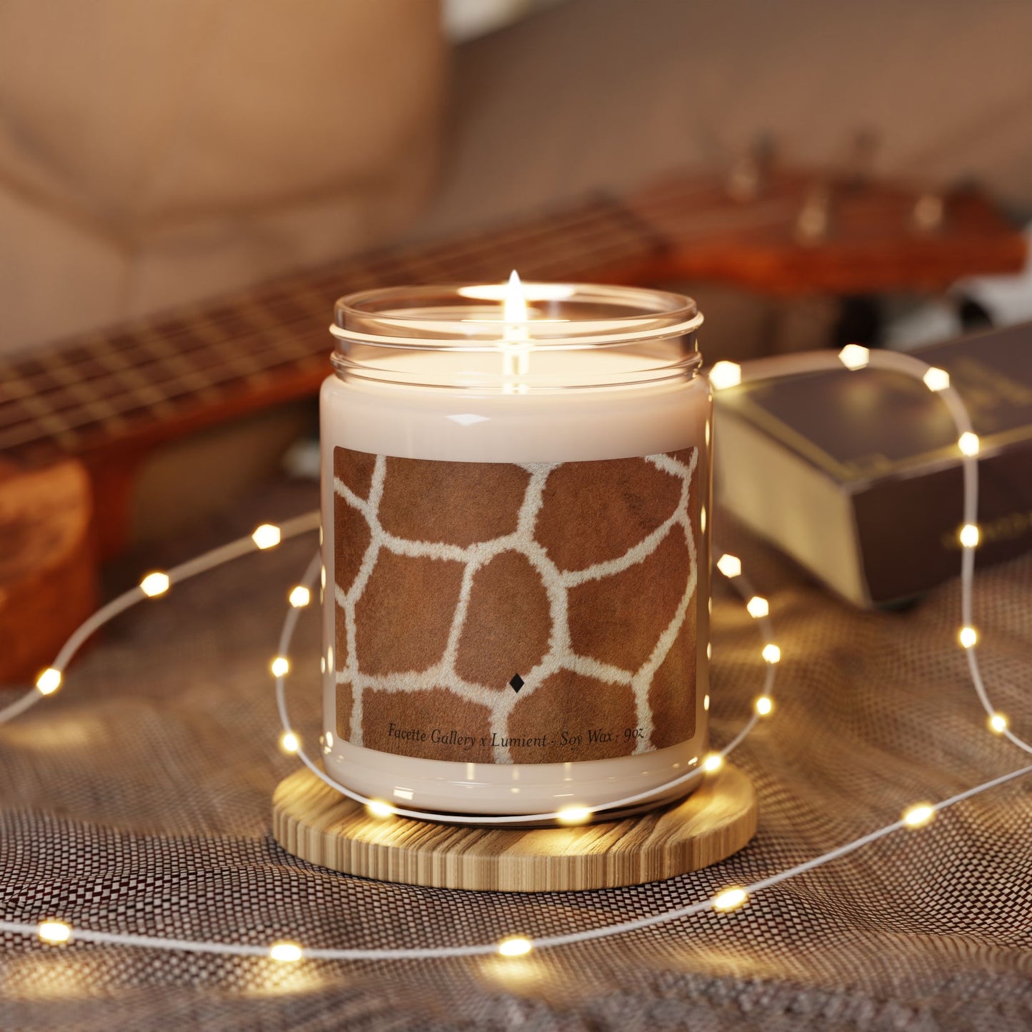 Lit giraffe print soy candle in 9oz glass jar on wooden coaster with fairy lights and guitar background