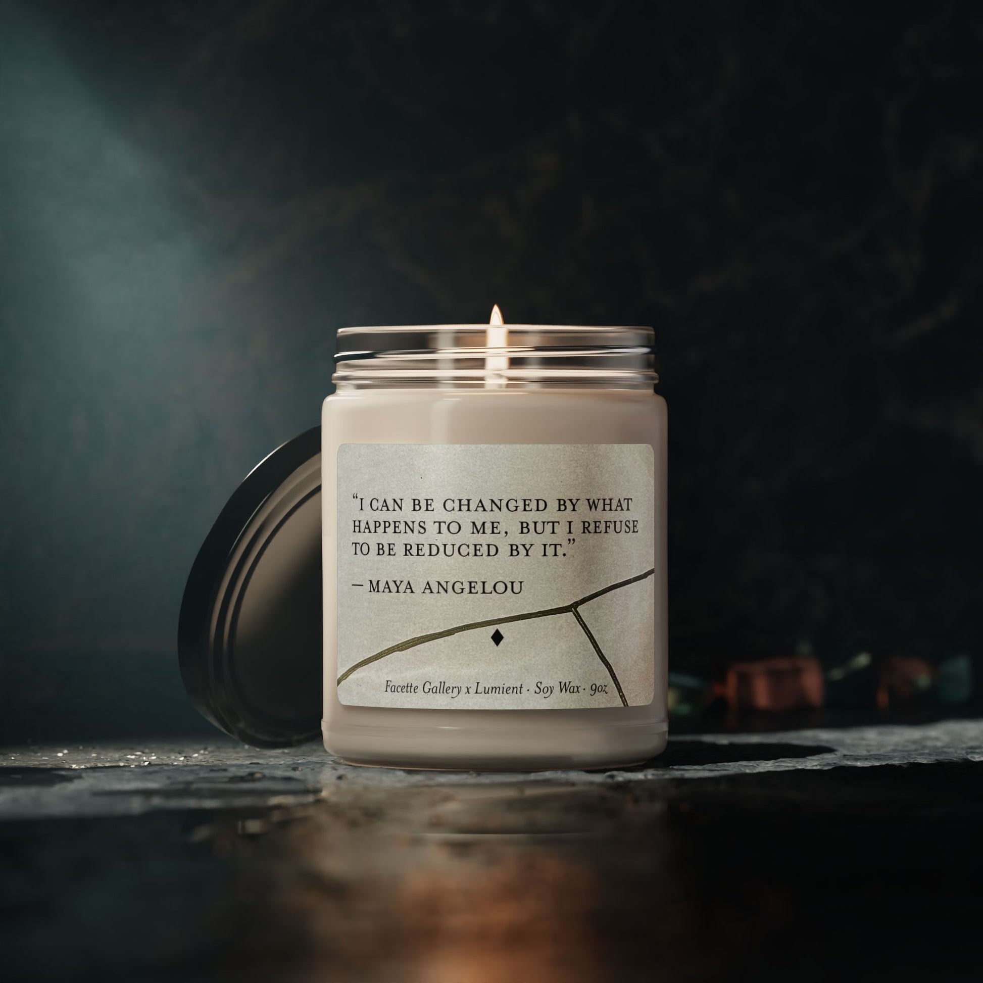 Lit 9oz soy candle in glass jar with Maya Angelou quote and Kintsugi art on label, black lid beside jar