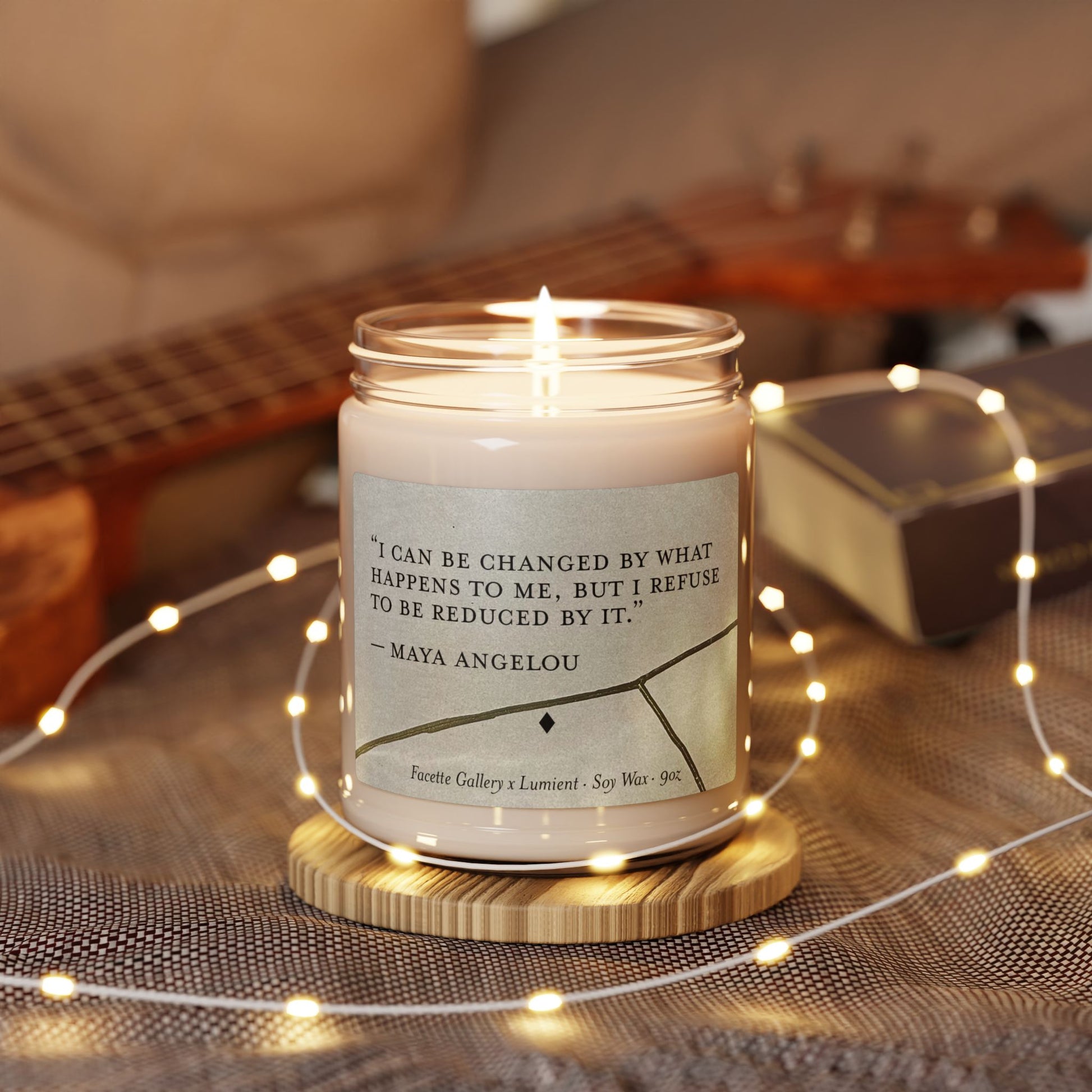 Soy candle in glass jar with Maya Angelou quote and Kintsugi art, surrounded by fairy lights on fabric surface