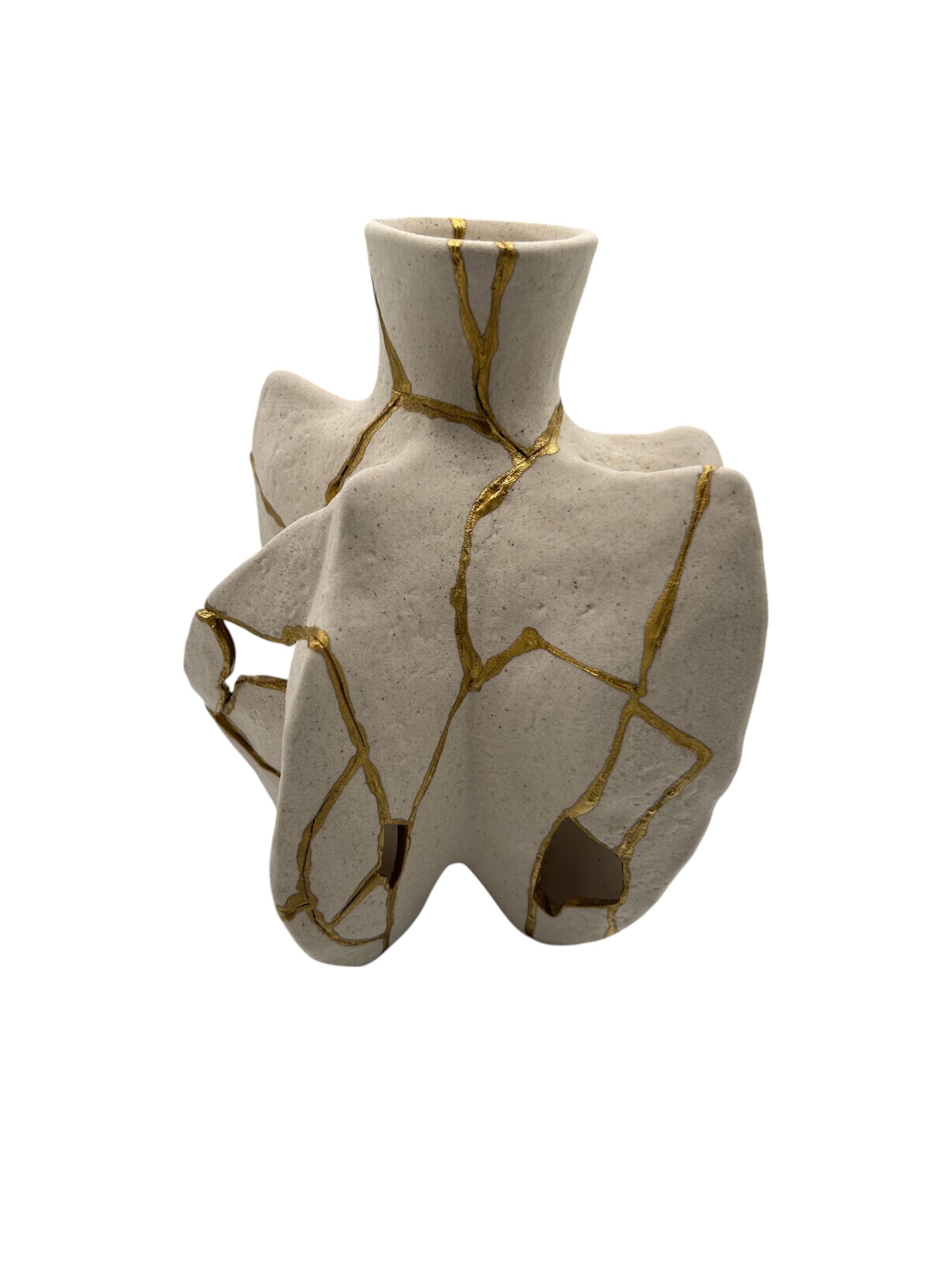 Modern kintsugi fossil vase with irregular shape and gold hand-painted cracks on ivory ceramic, 6.5in tall by 3.75in wide.