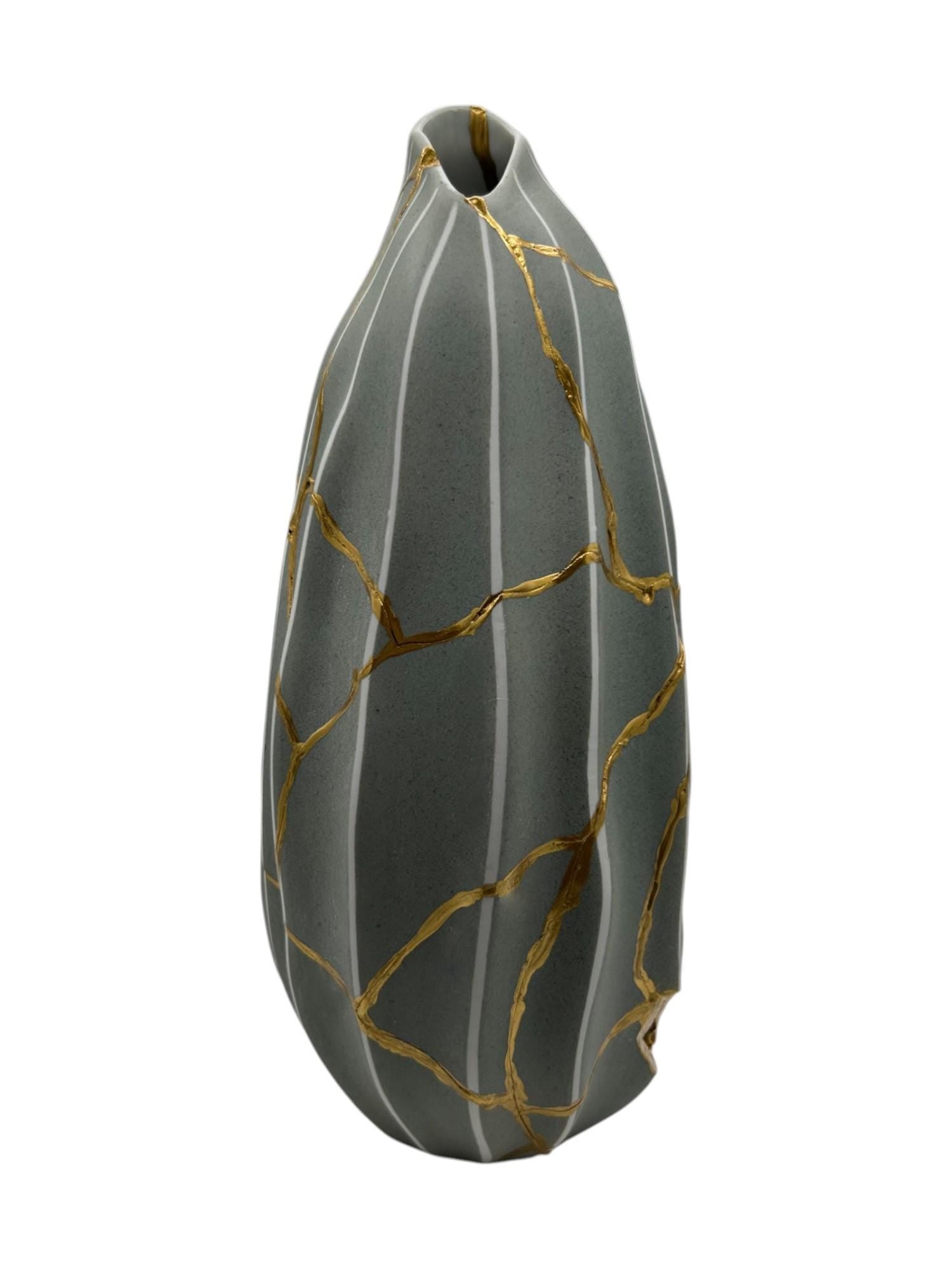 Modern gray melon-shaped ceramic vase with hand-painted gold kintsugi repair lines on white background.