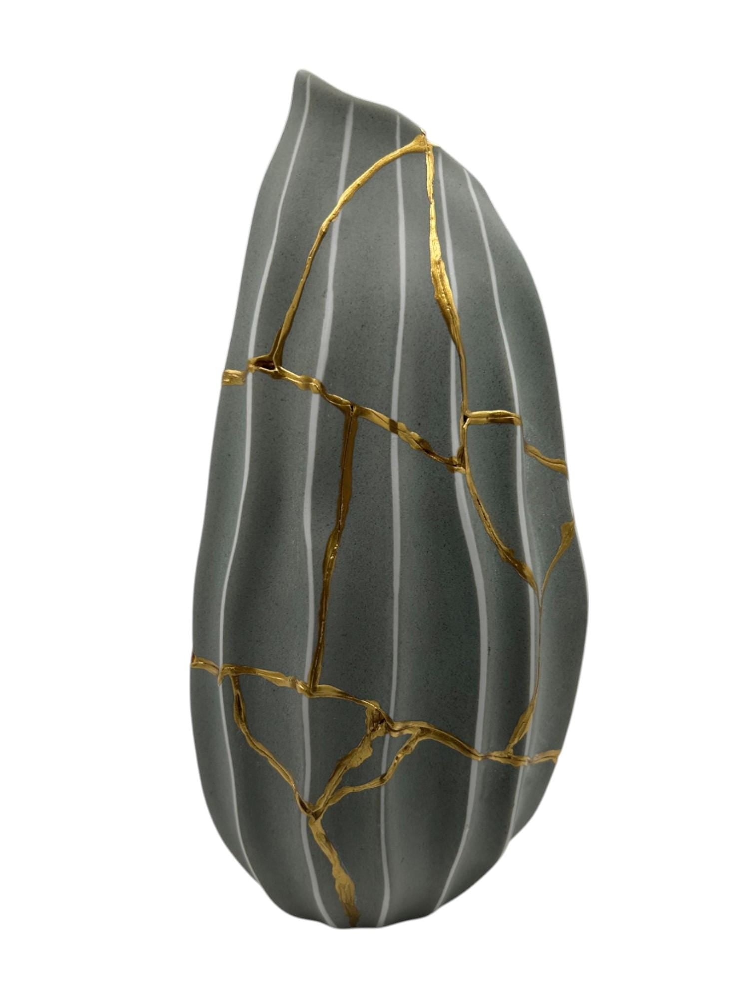 Modern kintsugi melon vase in green with white stripes and gold hand-painted repaired cracks on white background