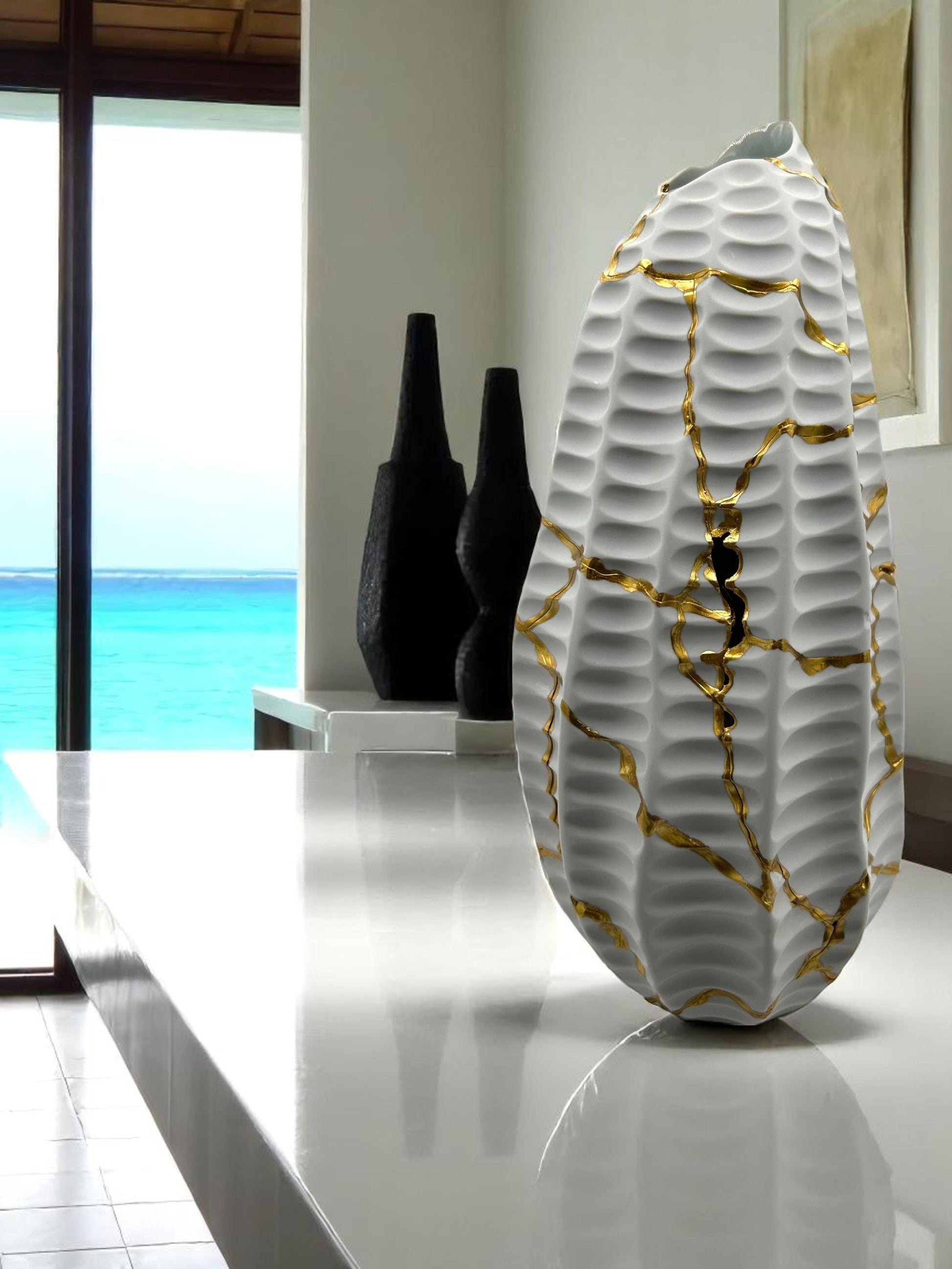 Modern white kintsugi seahorse vase with hand painted gold repairs, textured surface, and 12-inch height on white counter.