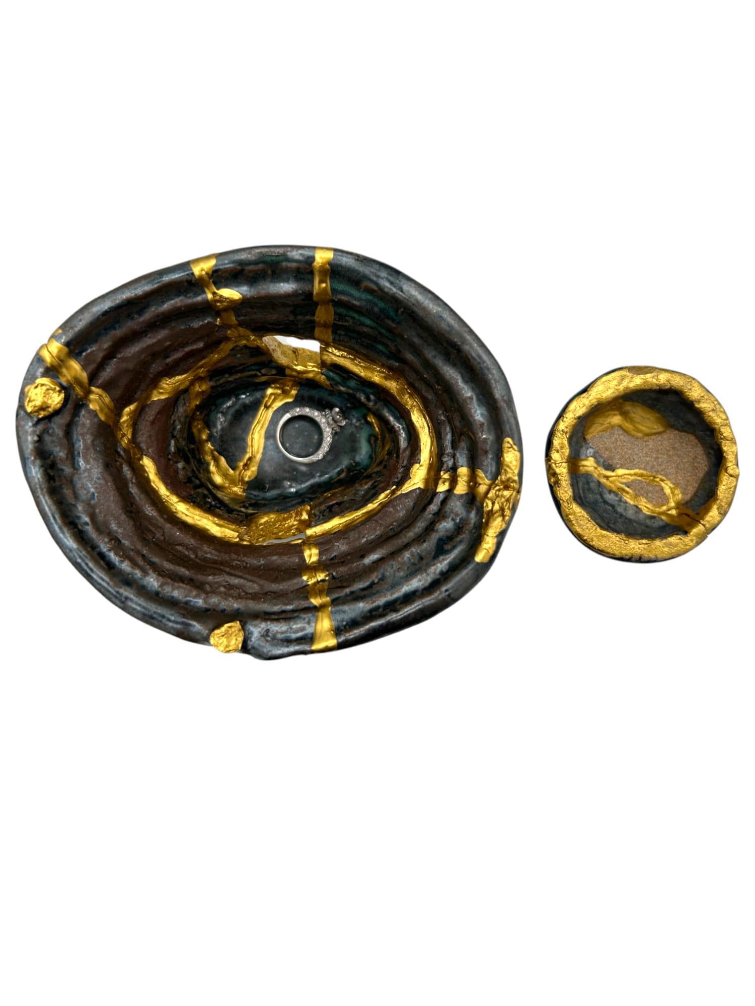 Two-piece modern Kintsugi bowls in dark ceramic with hand-painted gold repair lines on a white background.