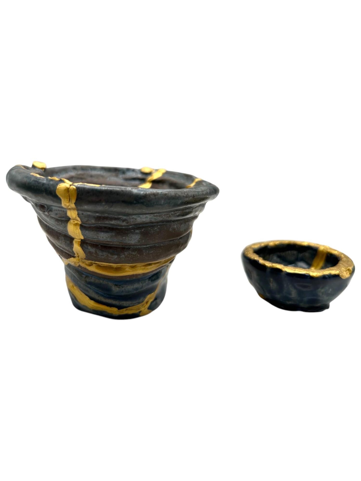 Two-piece set of modern black ceramic Kintsugi bowls with hand-painted gold repairs on white background
